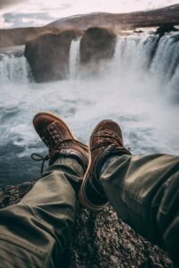 Person Sitting on Rock Near Waterfalls